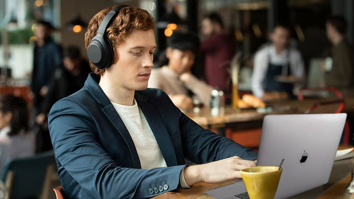 man wearing Sony headphones on Mac laptop