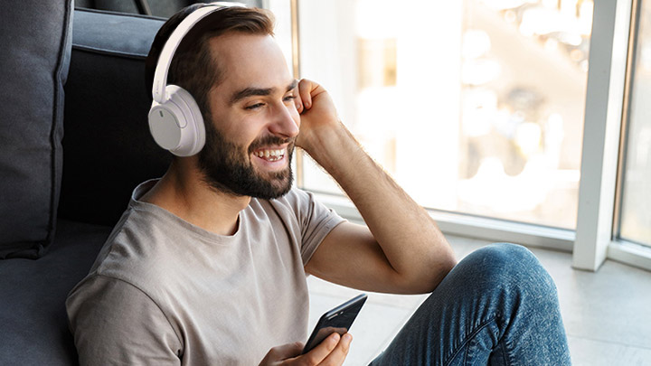 Man wearing Sony headphones and holding phone