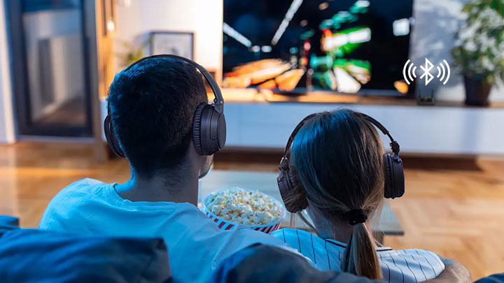 Man and woman watching TV with headphones